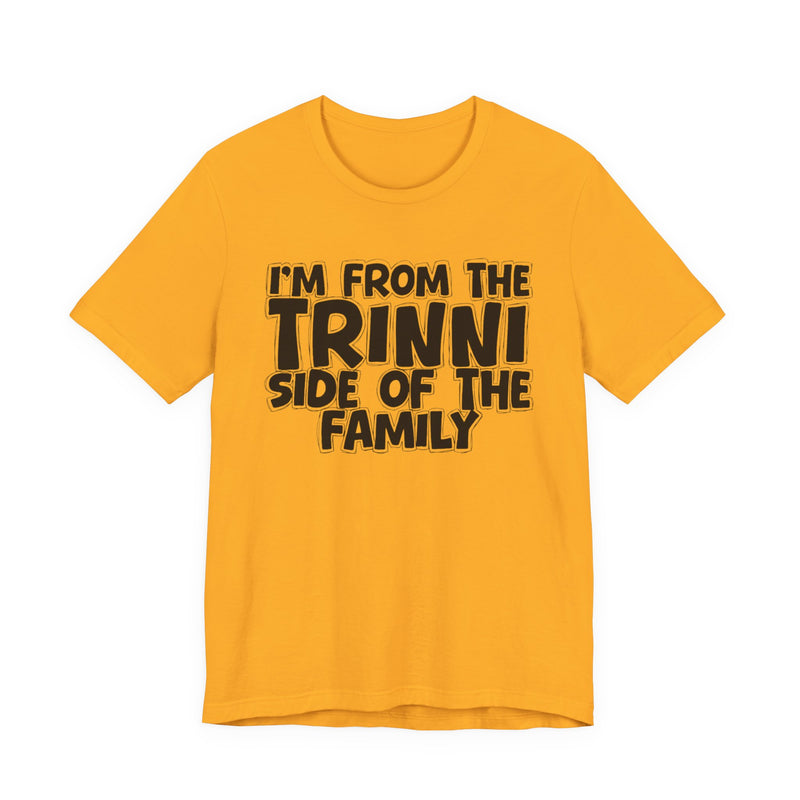 Gold t-shirt with 'I'M FROM THE TRINNI SIDE OF THE FAMILY' in black hand-drawn bubble lettering on the chest, front flat-lay mockup view.