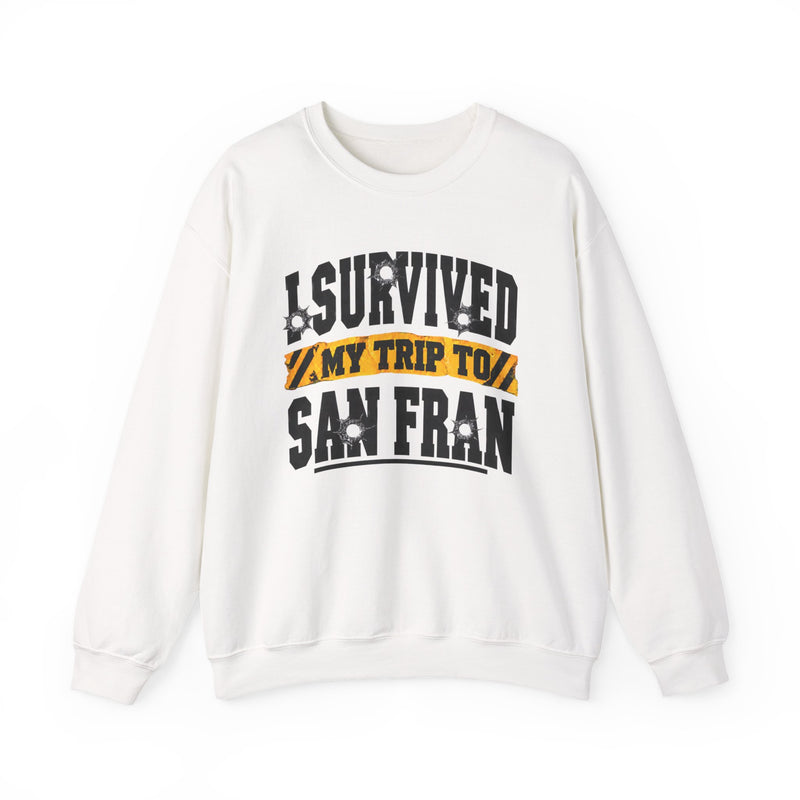 White sweatshirt with black block lettering reading I SURVIVED MY TRIP TO BALTIMORE, with bullet-hole accents and a yellow caution-tape banner, front flat-lay view.