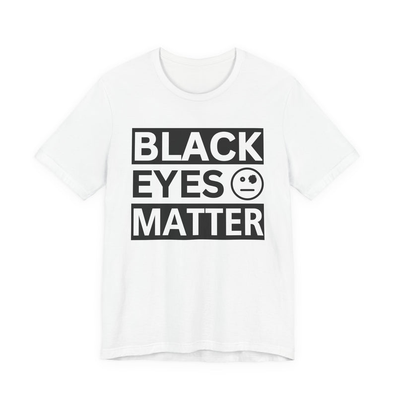 Olive t-shirt with ‘BLACK EYES MATTER’ in boxed block lettering with a smiley-face eye icon graphic in light-contrast print, front flat-lay mockup view