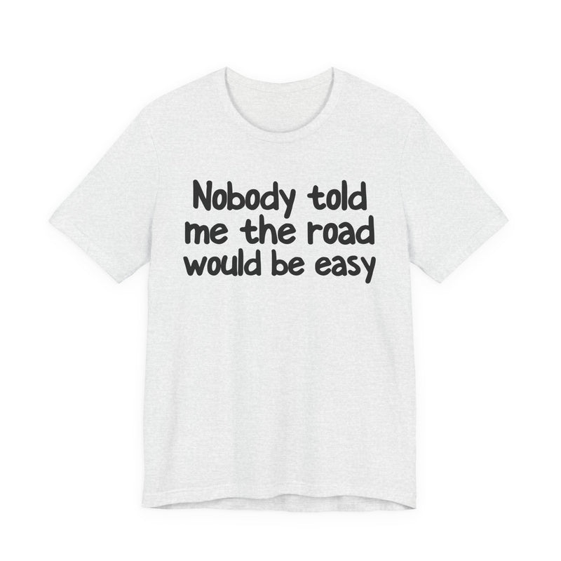 T-Shirt with text design reading “NOBODY TOLD ME THE ROAD WOULD BE EASY”, front view