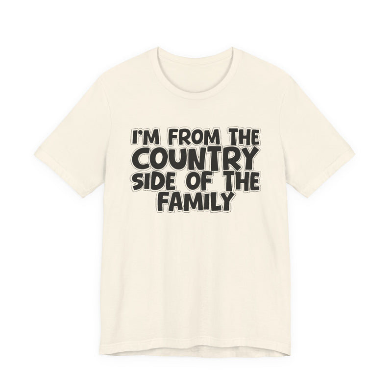 Natural t-shirt with white outlined bubble lettering reading 'I'M FROM THE COUNTRY SIDE OF THE FAMILY', front flat-lay view.