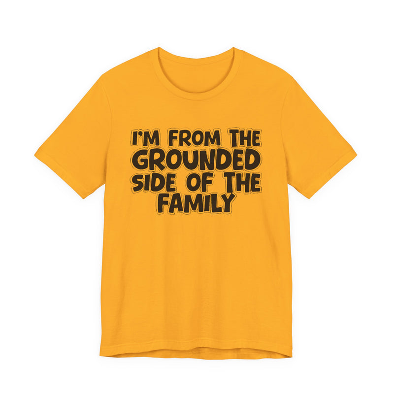 Gold t-shirt with 'I'M FROM THE GROUNDED SIDE OF THE FAMILY' in black hand-drawn bubble lettering on the chest, front flat-lay mockup view.