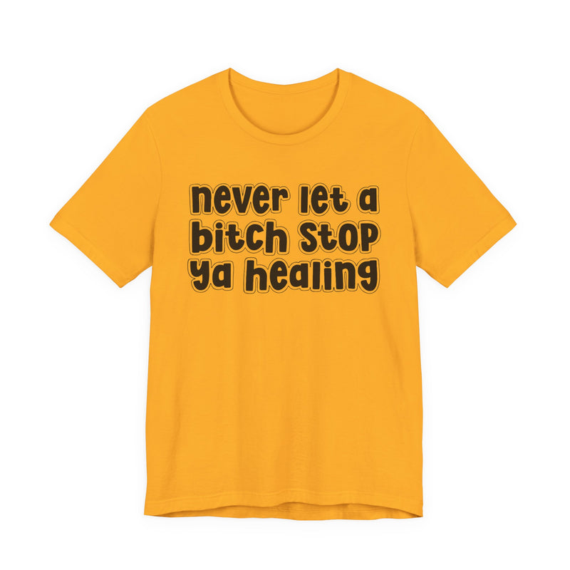 Graphic t-shirt with bold statement lettering reading "NEVER LET A BITCH STOP YA HEALING", front view, product mockup